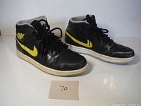 Pair of black and yellow Air Jordan 1 sneakers front and side angle showing general condition and size 7.5 indication.