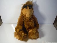 Full body image of the ALF plush toy in sitting position with visible limbs and body fur texture.