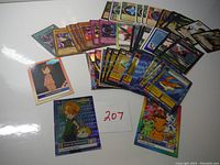 A variety of Digimon, Yu-Gi-Oh, and Magic the Gathering trading cards spread out showing different card types and colors.