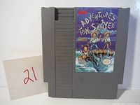 Front side of the Nintendo NES cartridge showing Adventures of Tom Sawyer label with colorful illustrated characters and title text.