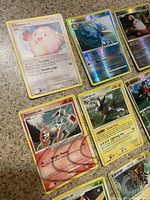Close-up of nine Pokemon cards showing Chansey, Golduck Holo, Arceus Holo, Luxray Holo, Kadabra Holo among others