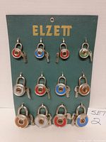 Front photo showing 12 Elzett branded padlocks with keys mounted on green display board labeled SET 2.