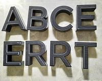 Front view of the 8 black textured letters A, B, C, E, F, R, R, T showing LED light installation in each.