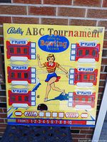 Front view of colorful Bally ABC Tournament arcade game back glass panel featuring bowling game graphics with six player score displays and illustrated woman bowling.