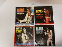 Four Elvis Presley 45 RPM records with original picture sleeves, showing front artwork and titles.