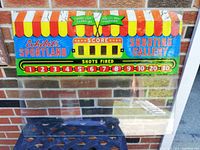 Front side of the Exhibit Sportland Shooting Gallery arcade back glass panel showing colorful canopy graphics, score display area, and shot numbers with bright colors