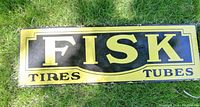 Front view of rectangular yellow and black Fisk Tires & Tubes sign.
