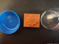 Orange rubber stamp with Toronto Maple Leafs logo reversed on rubber, blue plastic capsule parts next to it