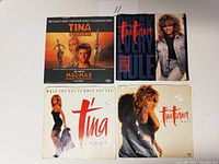 Front view of four Tina Turner 45 RPM record sleeves laid out flat, showing colorful artwork and portraits.