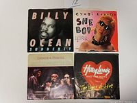 Four 45 RPM records with original picture sleeves, featuring Billy Ocean, Cyndi Lauper, Dione & Friends, Huey Lewis and the News.