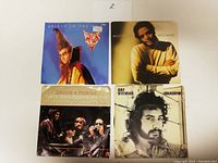Four 45 RPM vinyl records in original picture sleeves front view showing artist images and album titles