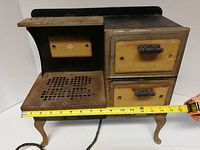 Full front view of the salesman sample Empire Stove with tape measure showing width approximately 15 inches.