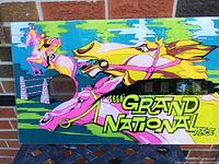 Front view of the colorful Sega Grand National Race back glass showing horse racing artwork and title.