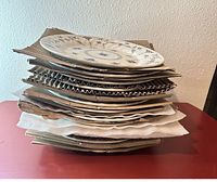 Stack of various plates, bowls, and cloth padding showing blue floral patterned porcelain dishes packed with cardboard.