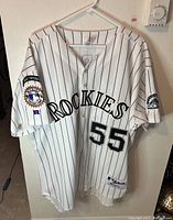 Front view of white Colorado Rockies jersey with pinstripes, number 55, and embroidered patches on sleeves