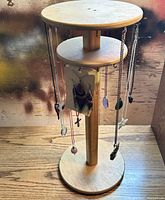 Wooden rotating jewelry stand with necklaces and earrings hanging, showing overall lot contents
