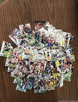 Spread of football cards showing many player action shots and portraits on wooden table.