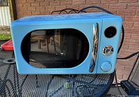 Retro blue Galanz microwave with closed door on black metal table
