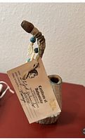 Front and side views of the Native American wood pipe, showing its detailed craftsmanship, decorative beads, and ceramic leaves attached to the stem.