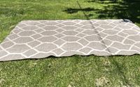 Gray geometric patterned 8x10 rug photographed outdoors on grass to show full size and pattern.