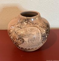 Photo of a southwestern style vase with eagle head design in tan and black with geometric etchings.