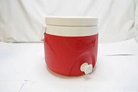 Red Coleman 2 gallon water jug with spigot and white lid shown from side angle.