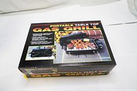 Top view of closed box showing product branding and picture of grill with food on it.