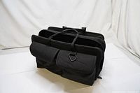 Photo of the black professional tool bag with two large zipped pockets and carrying handles, viewed from the side.