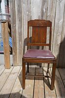 Front view of vintage wooden dining chair showing carved backrest and upholstered seat.