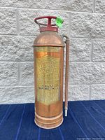 Front full view of antique soda acid fire extinguisher showing general condition and attached hose.