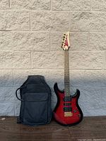Full view of Yamaha electric guitar in red sunburst finish next to included soft carrying case