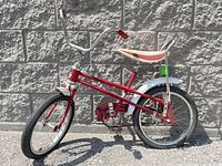 Side view of the full red kids banana seat bicycle showing chrome fenders, padded banana seat, and wide handlebars