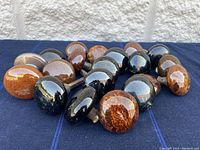 Full set of 20 polished marble antique doorknobs laid out on a dark cloth background, showing color and finish variations.