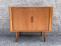 Front view of closed teak cabinet on four tapered legs
