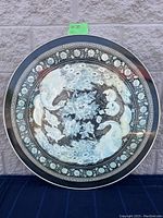 Front view of round table top showing detailed peacock, turtle, and floral oriental artwork.