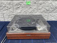 Front view of Pioneer turntable with wood grain finish and dust cover on.