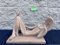 Full view of the reclined nude female ceramic sculpture with rectangular base, showing the figure's pose and hat.