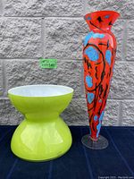 Lot overview showing both the green hourglass-shaped bowl by Anne Nilsson and the tall red hand-painted vase with blue and black accents.