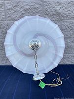 Top-down view showing the scalloped edge and swirl pattern of the glass lamp shade along with chain and ceiling mount hardware visible inside.