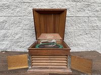 Full view of vintage gramophone with top lid and front doors open, showing wooden casing and louvered front panel.