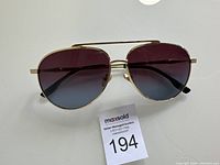 Front view of aviator sunglasses showing gradient purple lenses and gold frame.