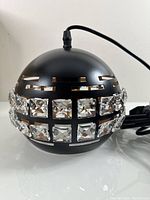 Front-side view of the black spherical pendant light with two rows of square crystal inserts, attached power cord visible.