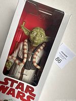 Clear front view of Yoda figure inside unopened Star Wars branded box, showing figure and packaging condition.