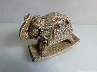 Front-side view of the vintage wooden elephant figurine showing the detailed carvings and white-painted patterns.