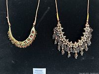 Both vintage necklaces displayed side by side on a black background, showing detailed front view of designs and stones.