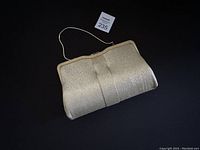 Photo of the vintage light gold silk clutch bag lying flat with visible texture and subtle pleats