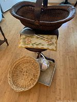 Full view of the three baskets with hooked rug, metal dustpan, small mirror, and miscellaneous items on a chair and floor.