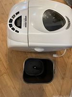 Top view of Black and Decker bread machine with control panel and removable bread pan on wooden floor.