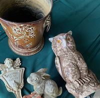 Group view of all items on a green surface including the bunny sculpture, clay owl, angel plaque, and embossed metal pail.