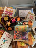 Photo showing the collection of various 70's items: vintage books, games, crocheted hat, art print, glasses, and penholder.